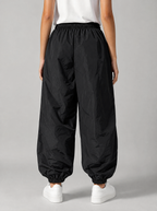 Back view of black parachute pants showing the elastic waist and cuffed ankles