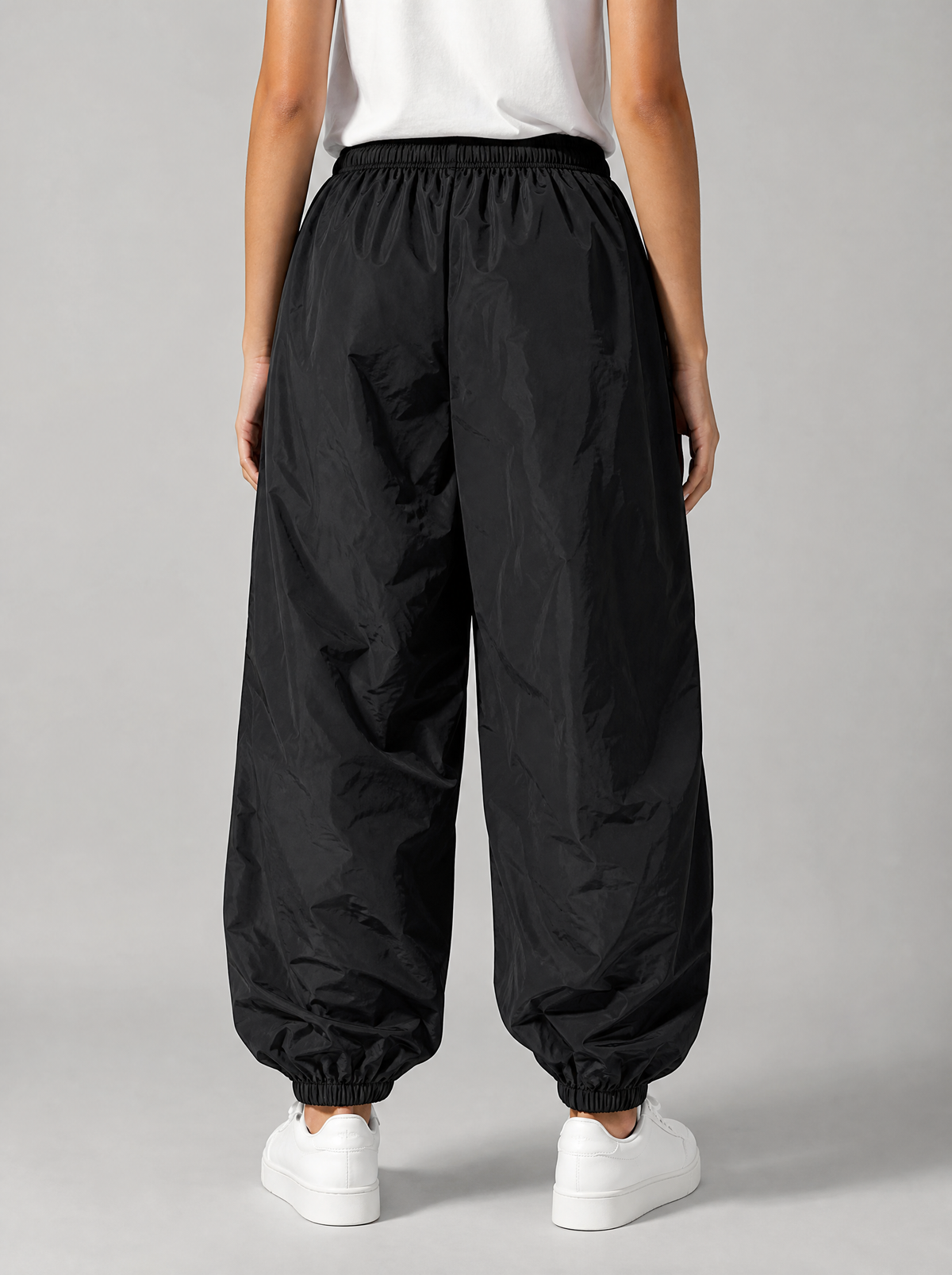 Back view of black parachute pants showing the elastic waist and cuffed ankles
