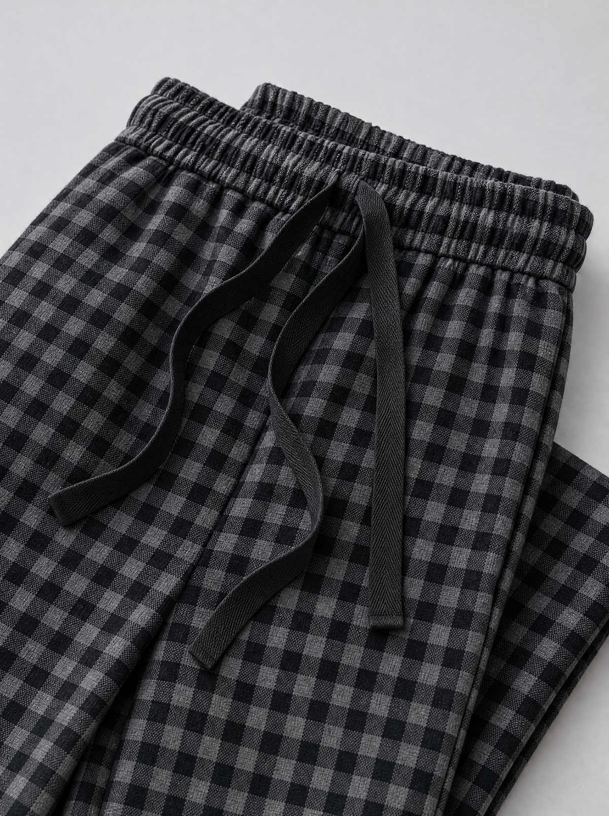Close up of the elastic drawstring waistband and check fabric on black wide leg pants