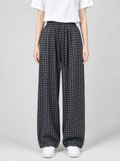 Woman wearing black check wide leg pants, front view on a light grey studio background