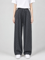 Woman wearing black check wide leg pants, front view on a light grey studio background