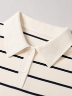 Close up of the pointed knit collar and thin navy stripe on a cream knit polo