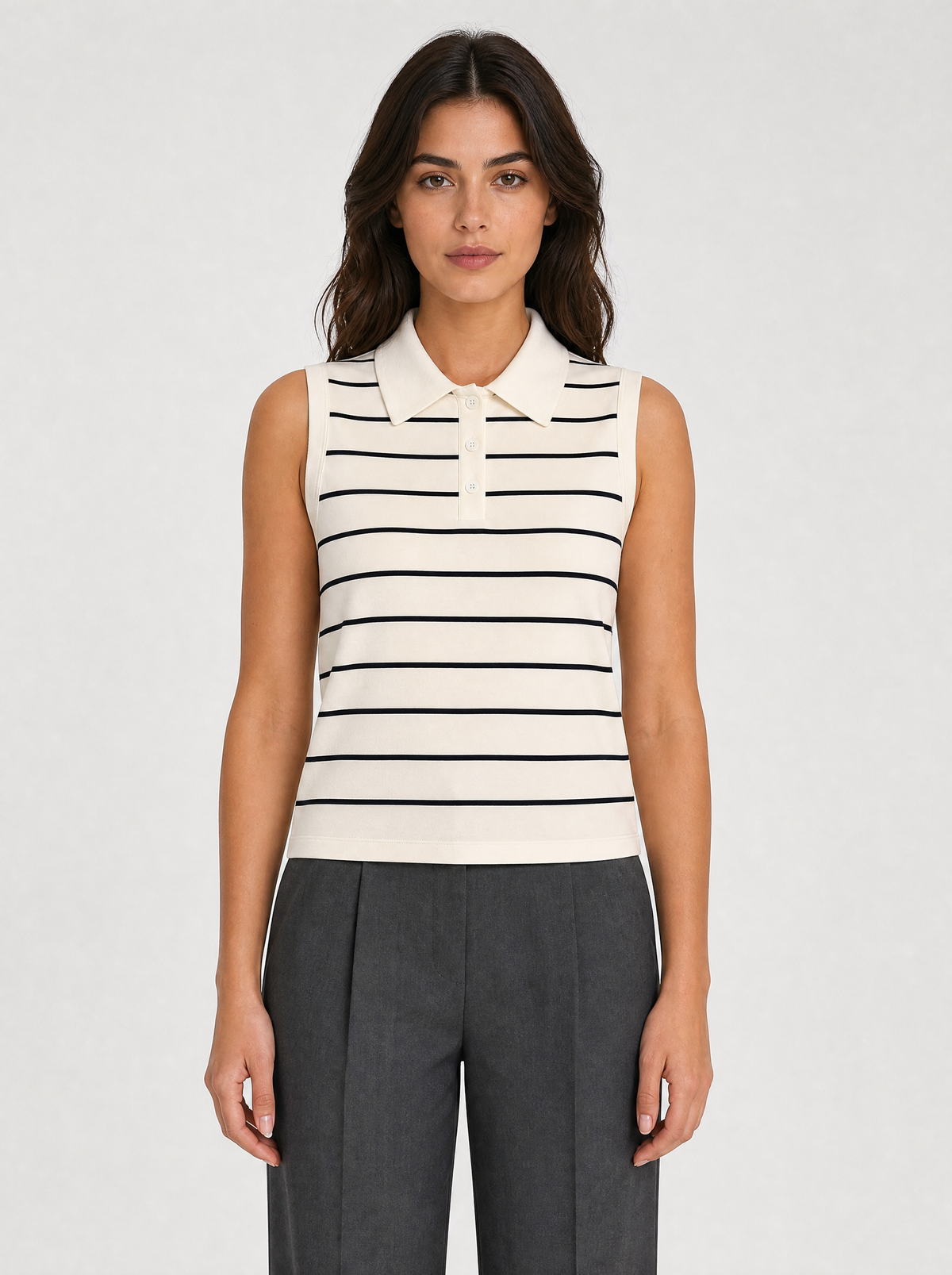 Woman wearing a cream striped sleeveless knit polo top, front view on a light grey studio background