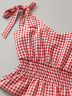 Close up of the tie shoulder strap and gingham check on a red peplum top