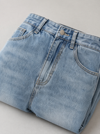 Close up of the waistband, shank button and pocket stitching on light wash jeans