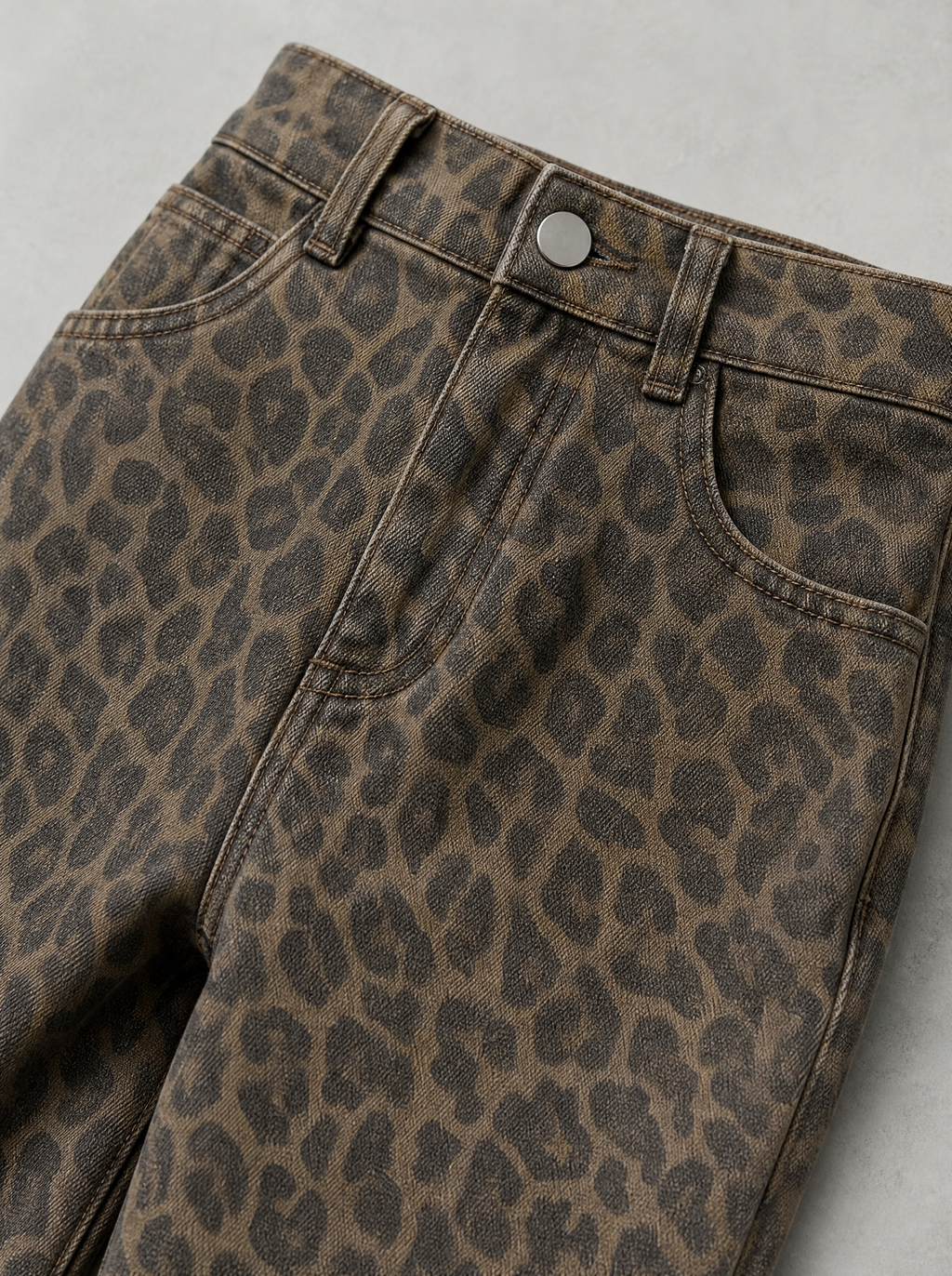Close up of the waistband, shank button and leopard print denim on wide leg jeans