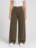 Woman wearing leopard print wide leg jeans, front view on a light grey studio background