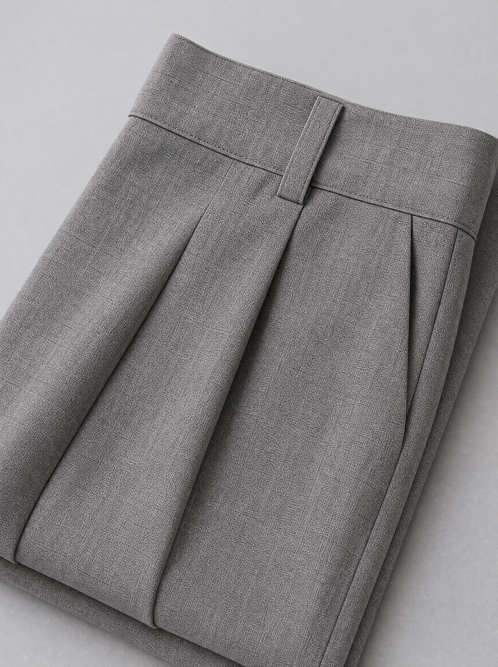 Close up of the waistband, belt loop and front pleat on grey tailored trousers
