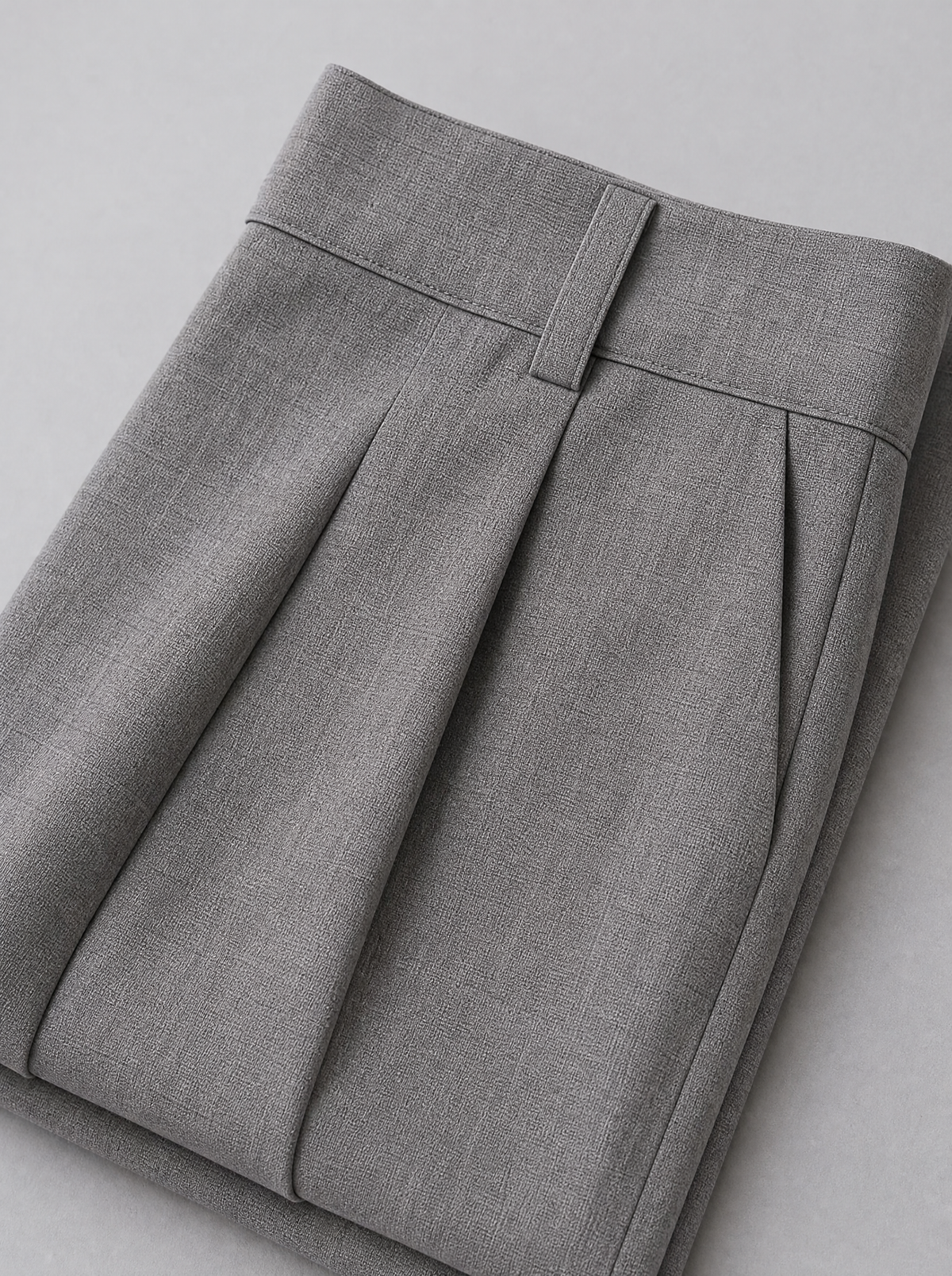 Close up of the waistband, belt loop and front pleat on grey tailored trousers