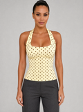 Woman wearing a yellow polka dot halter top, front view on a light grey studio background