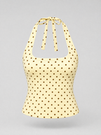 Yellow polka dot halter top shown on its own against a light grey background