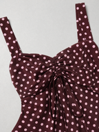 Close up of the drawstring ruching and polka dot print on a burgundy cami blouse