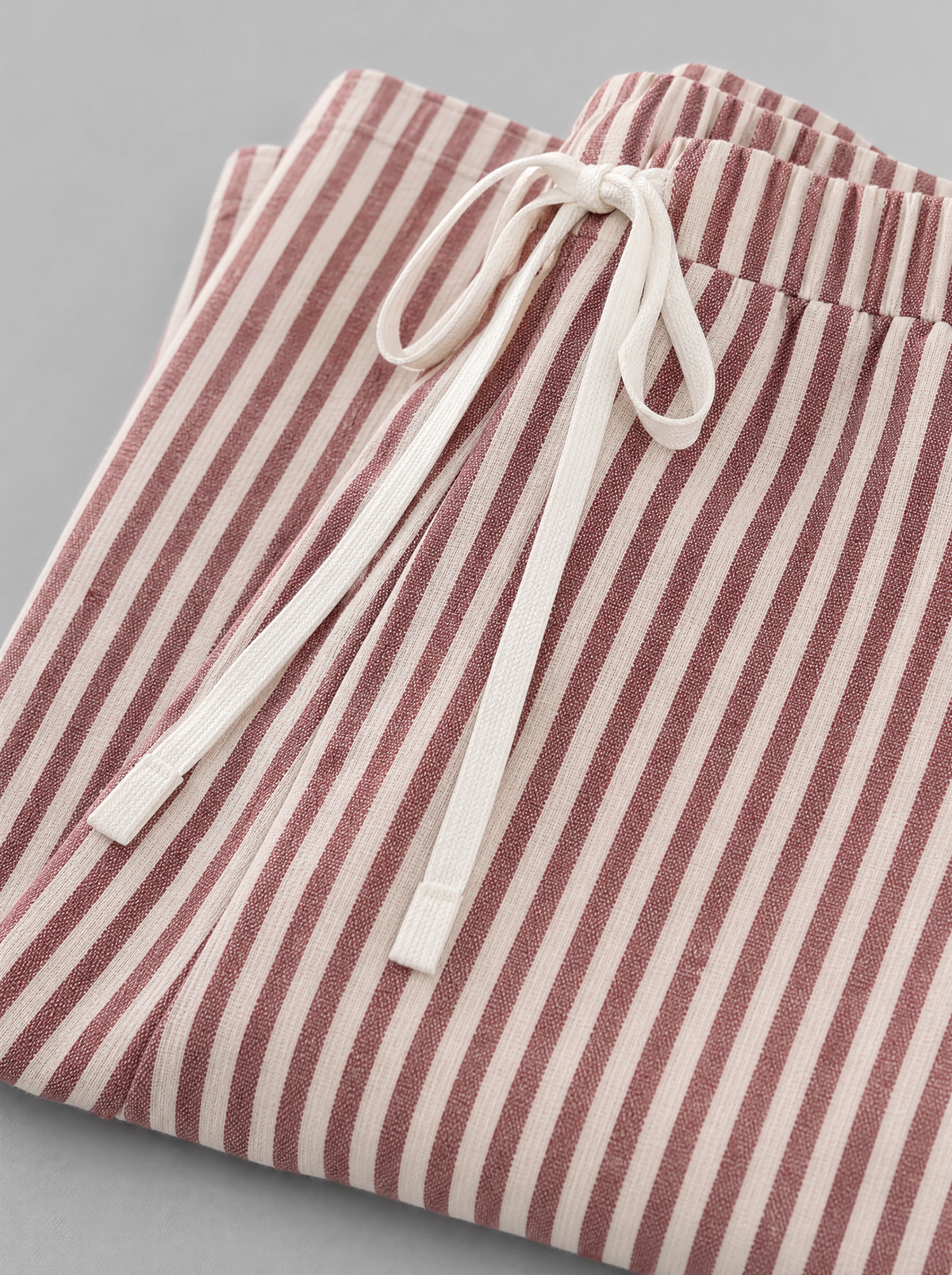 Close up of the white drawstring waistband and red stripe on lightweight wide leg pants