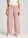 Woman wearing red striped wide leg pants, front view on a light grey studio background