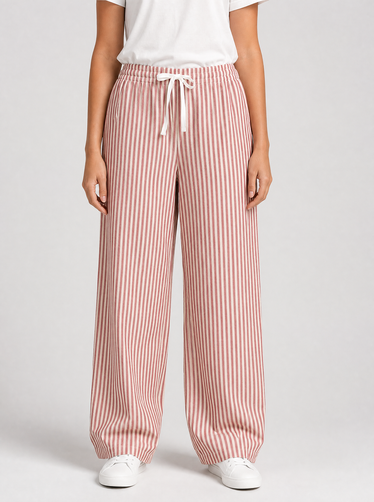 Woman wearing red striped wide leg pants, front view on a light grey studio background
