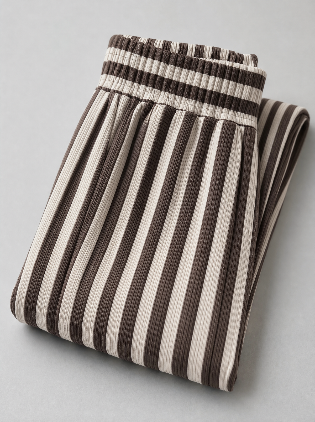 Close up of the elastic waistband and vertical rib knit stripe on brown knit pants