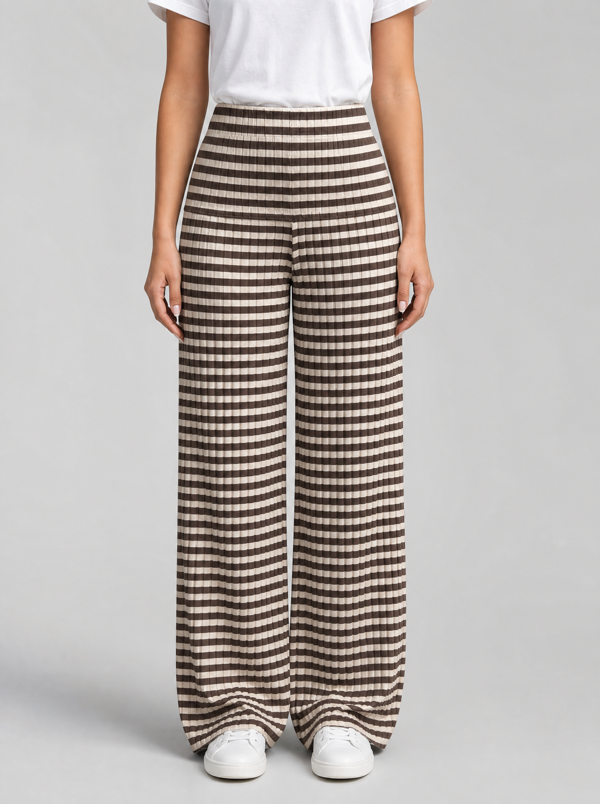 Woman wearing brown striped rib knit wide leg pants, front view on a light grey studio background