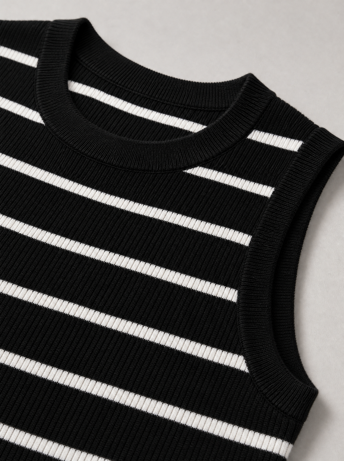 Close up of the ribbed crew neck and stripe on a black knit tank top